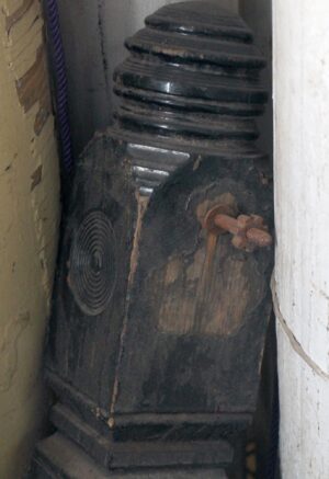 Traditional carved wood staircase newel post with a bulls eye detail shown in a close-up view.