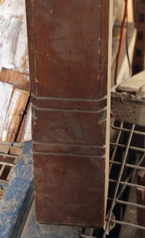 Traditional square staircase newel post in dark wood tone, shown in a close-up view with a carved band detail near the middle.