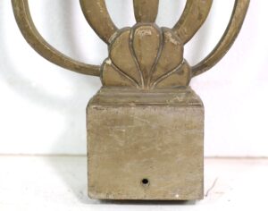 Close-up of an Art Deco brass balustrade with curved railing sections and a worn base, showing an antique patina and surface wear.