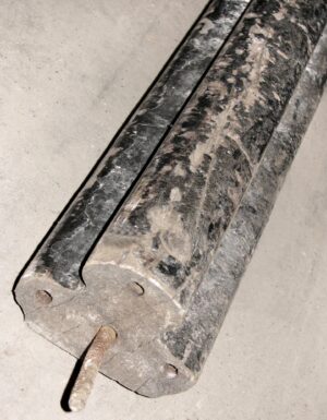Close-up of a reclaimed wooden banister with a black finish, showing the wide base and thin handrail with mounting holes.