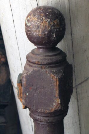 Antique traditional wooden staircase newel post with a carved ball tip and visible wear.