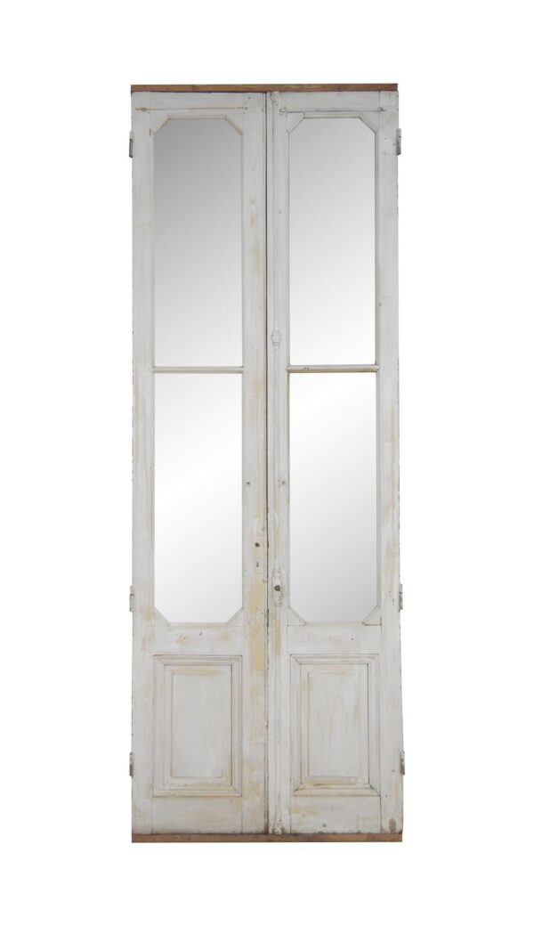 Tall white wooden double doors with two glass lites and a lower panel on each leaf, shown closed and front-facing.