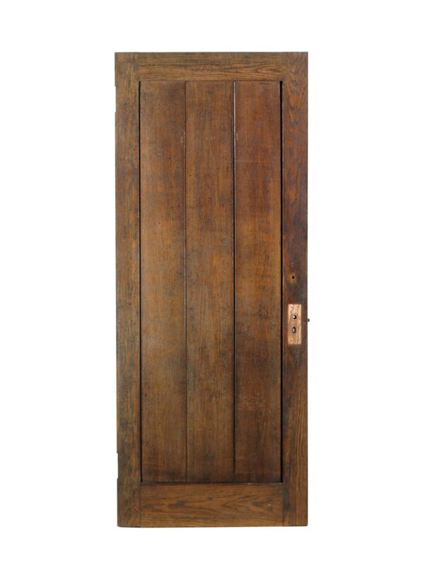Dark wood tone oak privacy door with one vertical panel of three boards and visible brass lock hardware on the right side.