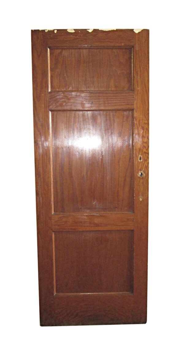 Three-panel oak door with a dark wood tone and recessed panels, shown upright with two lock holes on the right edge.