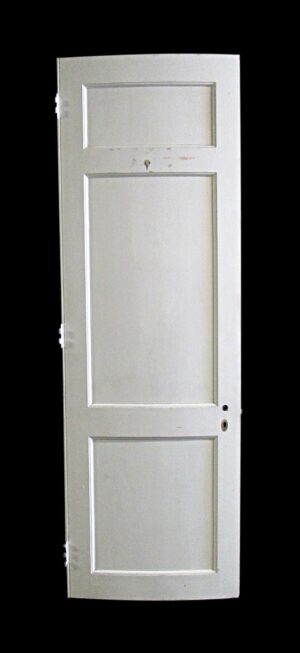 White wooden passage door with three recessed panels and some original hardware attached.