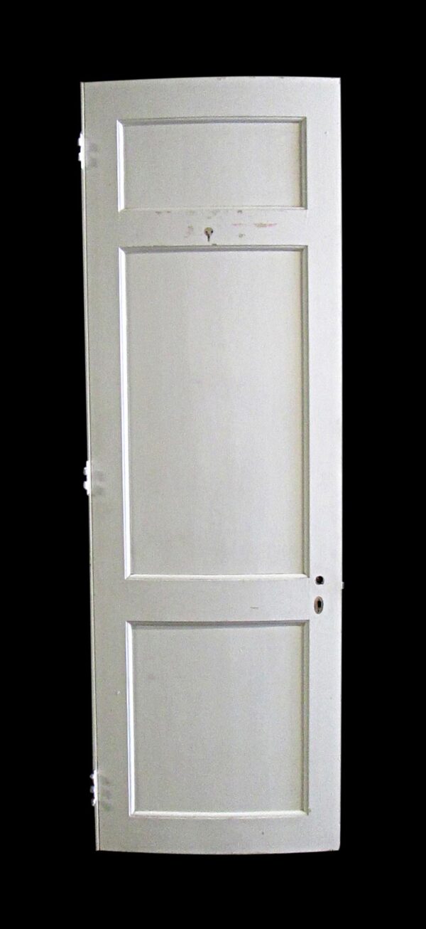 White wooden passage door with three recessed panels and some original hardware attached.