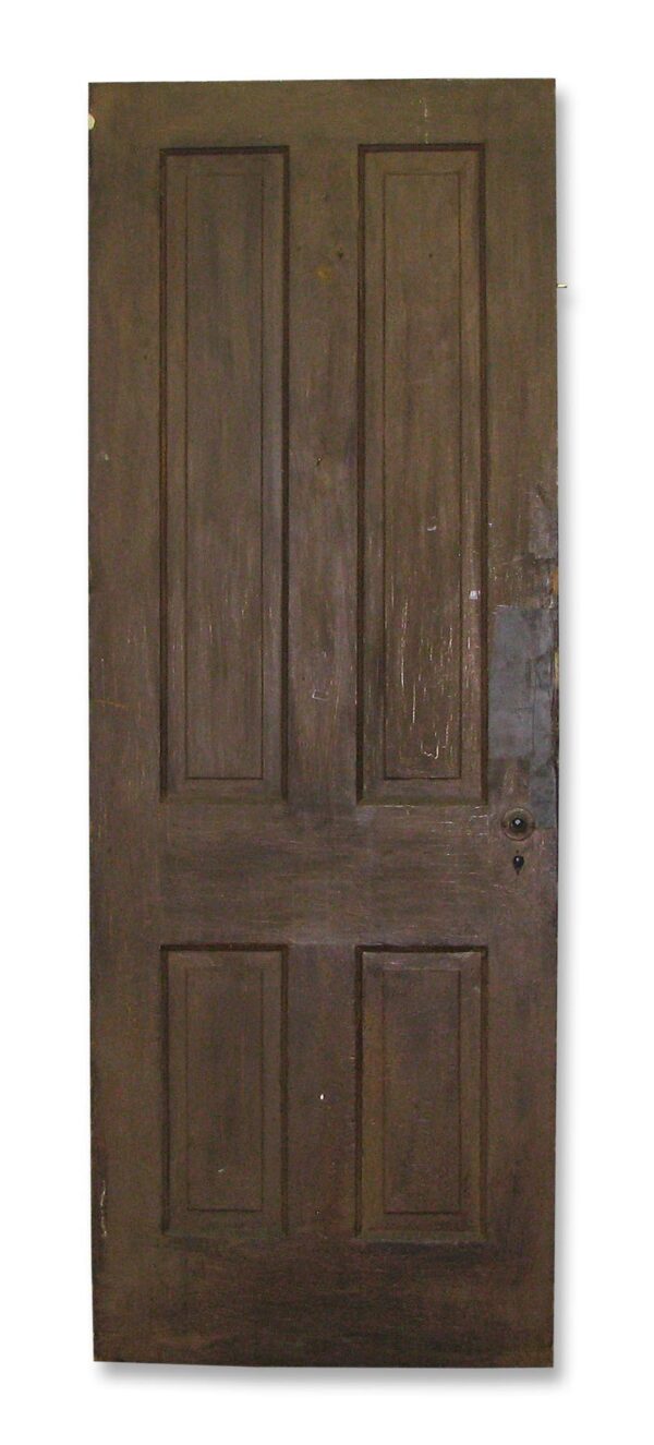 Antique four-panel wood door shown vertically with an original rim lock on the right side.