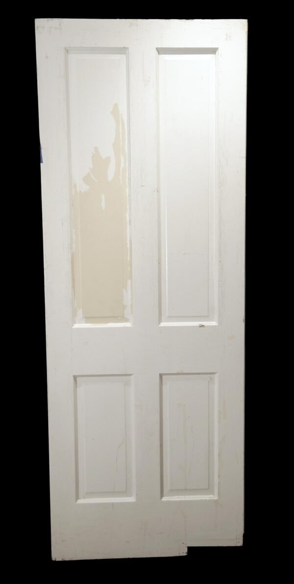 White wooden swinging door with four vertical panels and no hardware attached, shown full length with visible paint wear.