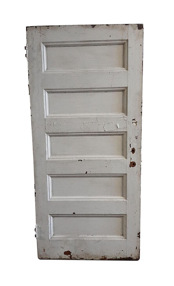 Antique wooden passage door with five horizontal panels, painted white on this side and showing worn edges and paint wear.