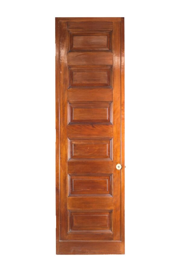 Tall wooden door with six horizontal panels and a round lock on the right edge.