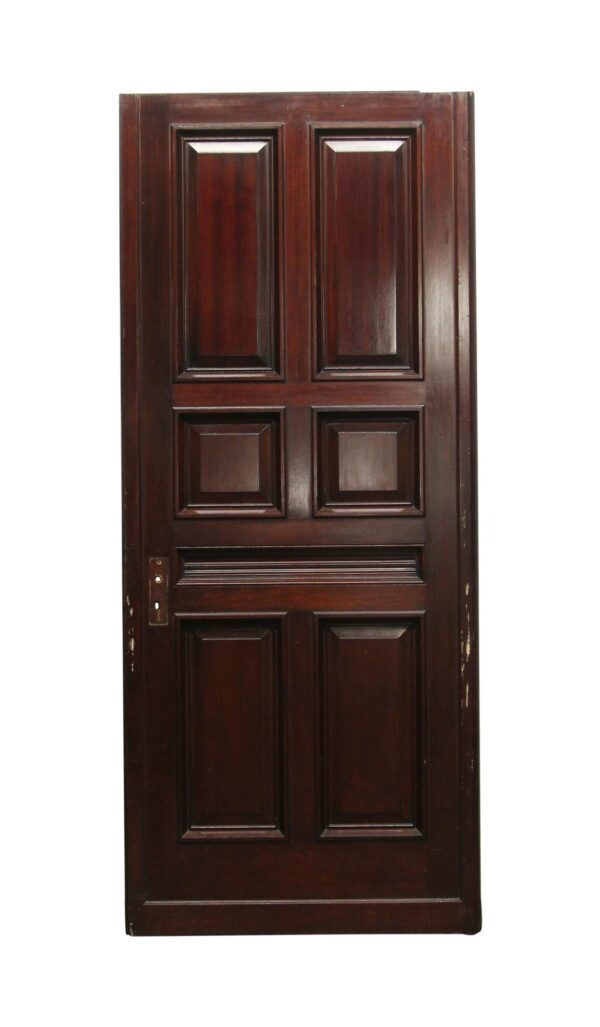 Tall wooden door with seven raised panels and a dark wood tone, shown front view with hardware opening cutout on the left side.