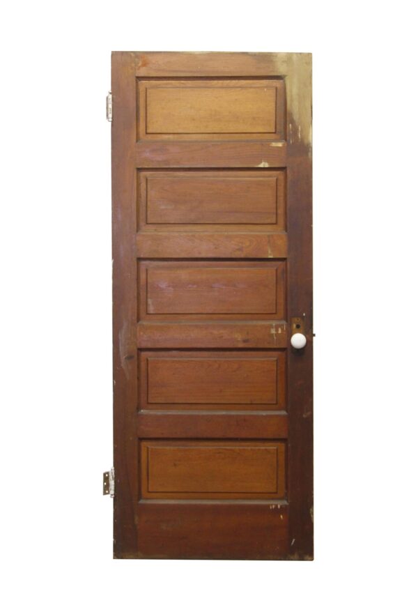 Vertical wooden passage door with five horizontal panels, a dark wood tone, and a round knob visible on the right side.
