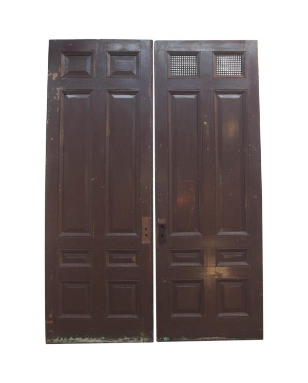 Pair of antique 8-panel double doors with a brown painted side, one door featuring vented top panels and visible wear.