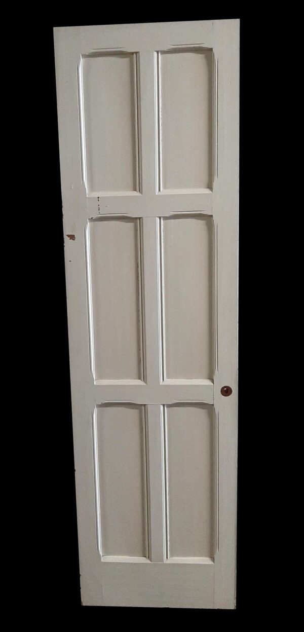 Narrow six-panel door painted white, shown upright with a round knob hole near the right edge.