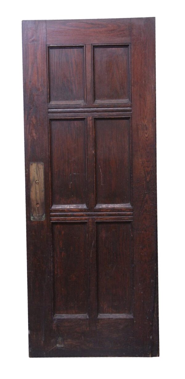 Dark wood tone oak door with six panels and a rectangular latch plate on the left side.