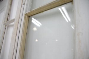 Close-up of a white wooden door showing a glass panel and painted frame detail.