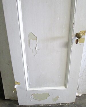 White wood passage door with one vertical panel, shown front-on with a right-swing configuration and visible paint wear on the surface.