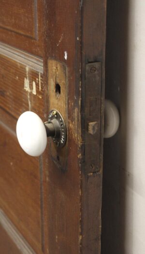 Close-up of a dark wood tone passage door with a white knob and visible latch hardware at the edge.