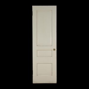 White painted wood passage door with three recessed panels and a round knob hole, shown full length with visible surface wear from prior use.
