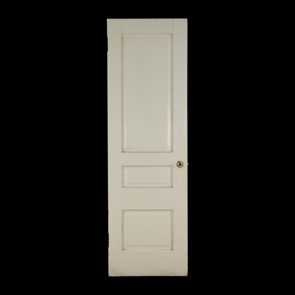 White painted wood passage door with three recessed panels and a round knob hole, shown full length with visible surface wear from prior use.