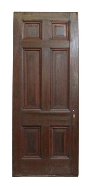 Dark wood tone six-panel wood door with a small lock hole on the right side and visible wear.