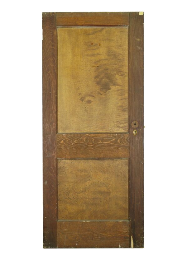 Two-panel pine passage door in a medium wood tone, shown vertically with brass hardware and visible surface wear.