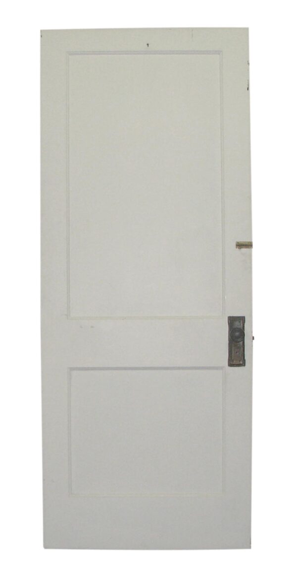 Vintage white wood privacy door with two recessed panels and visible hardware on the right side.