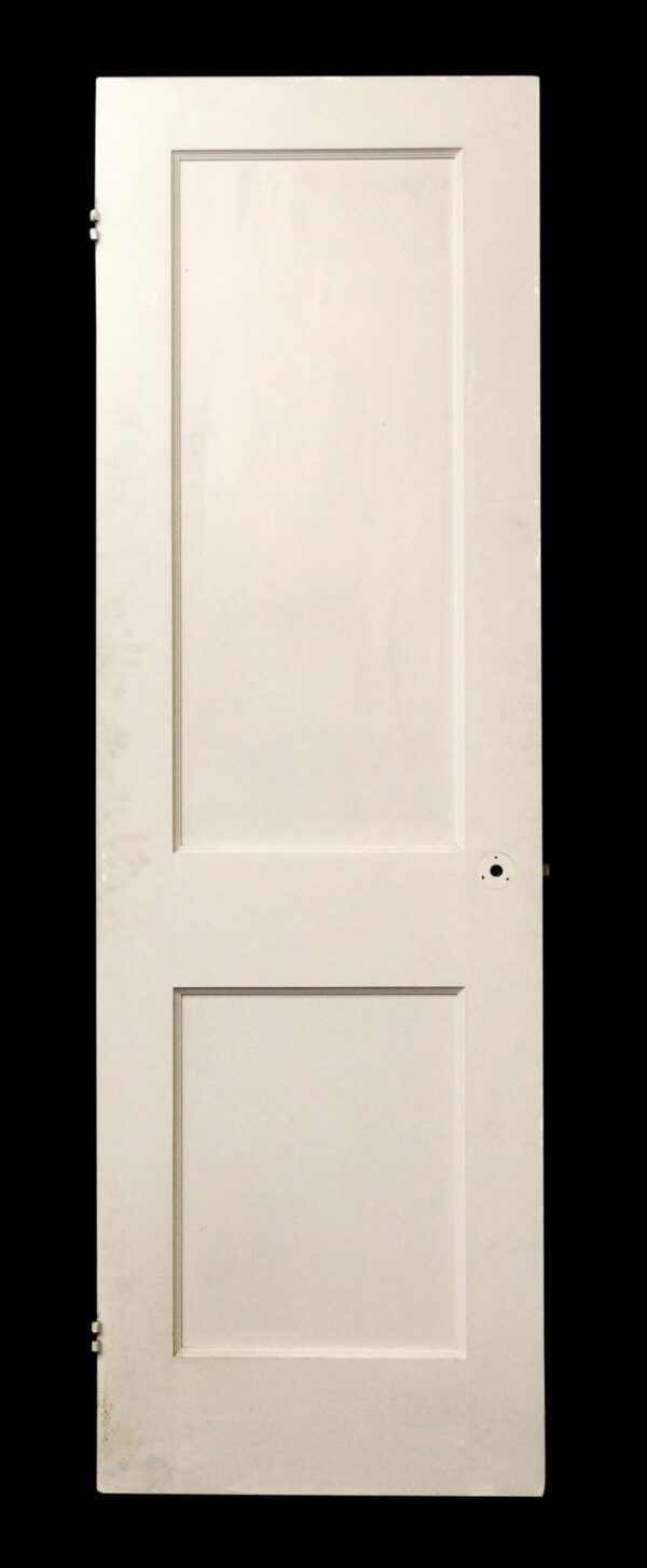 White wood closet door with two recessed panels, shown upright with hinge hardware visible on the left edge and a circular hole near the right side.