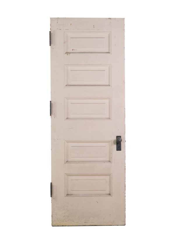 Tall tan pine passage door with five horizontal panels and original steel hardware.