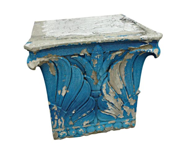 A blue limestone capital with a carved decorative face and weathered chipped edges, shown in close-up.
