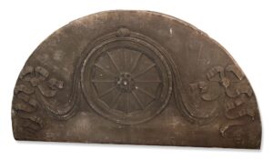 Gray Victorian limestone arched pediment with a central rosette and floral ribbon carving.