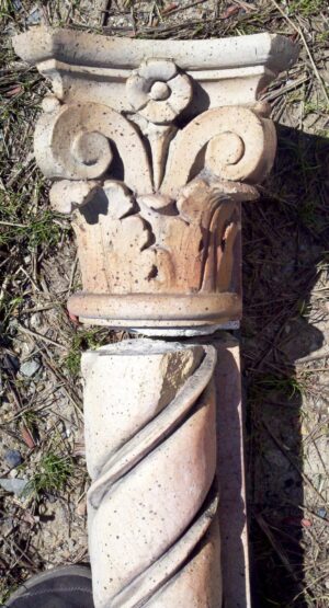 Decorative terra cotta pilaster capital and fluted shaft section with scroll and leaf details, shown in a close-up view.
