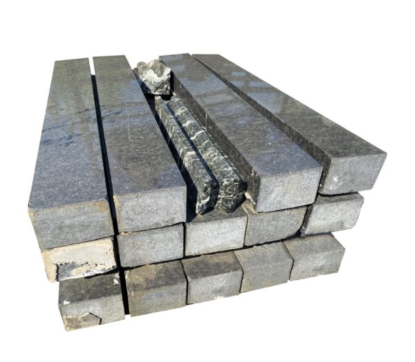 Stacked polished black granite slab blocks shown at an angle, with long rectangular pieces and smaller blocks visible in the front and center.