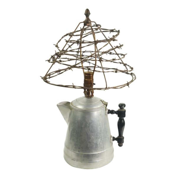 A table lamp made from a metal kettle with a barbed wire shade and black wooden handle.