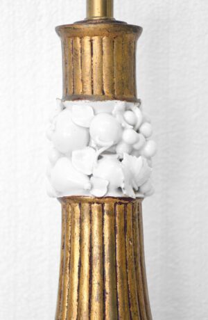 Close-up of a vintage table lamp with a gilt brass section and white ceramic fruit decoration around the center.