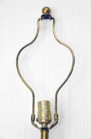 Close-up of a gold-finish table lamp base with a brass socket and curved metal arms.