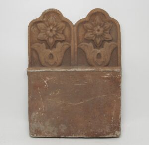 Pair of floral terra cotta pieces with twin raised flower designs above a plain rectangular base, shown as a single set.
