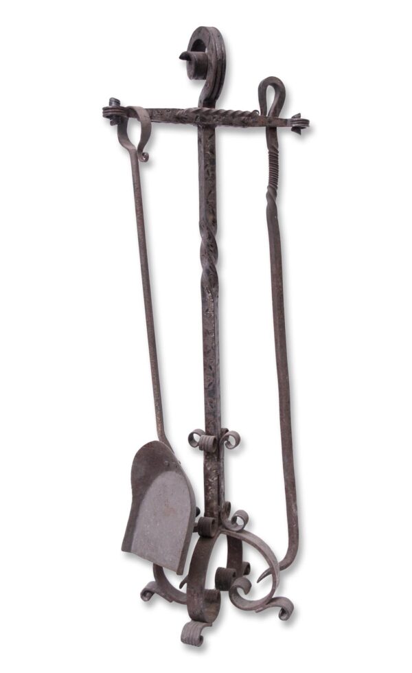 Antique wrought iron fireplace tool set with twisted and curled details, shown as a vertical holder with a shovel and one tool, missing two pieces.