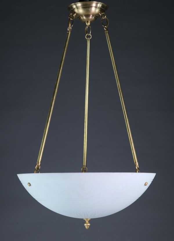 Modern white milk glass dish pendant light with etched floral motifs, suspended from a polished brass three-pole fitter and finished with an acorn finial.