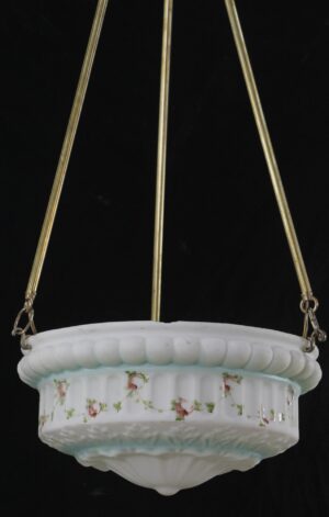 White cast glass pendant light with painted pink flowers and green vine details, suspended from three antique brass poles, shown with chips along the rim and visible stains.