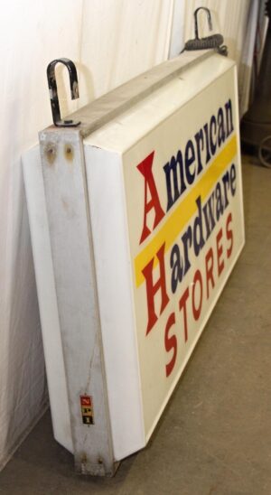 Vintage hanging hardware store sign with blue, red, white, and yellow lettering, shown at an angle with metal side brackets and a small crack on one side.
