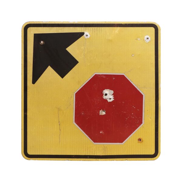 Vintage yellow metal road sign with a black left-pointing arrow and a red stop symbol, showing visible wear and peeling paint.