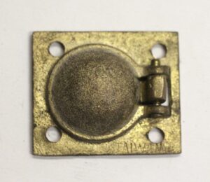 Antique brass recessed cabinet pull with a square faceplate, domed center, four mounting holes, and a small hinged tab on one side.