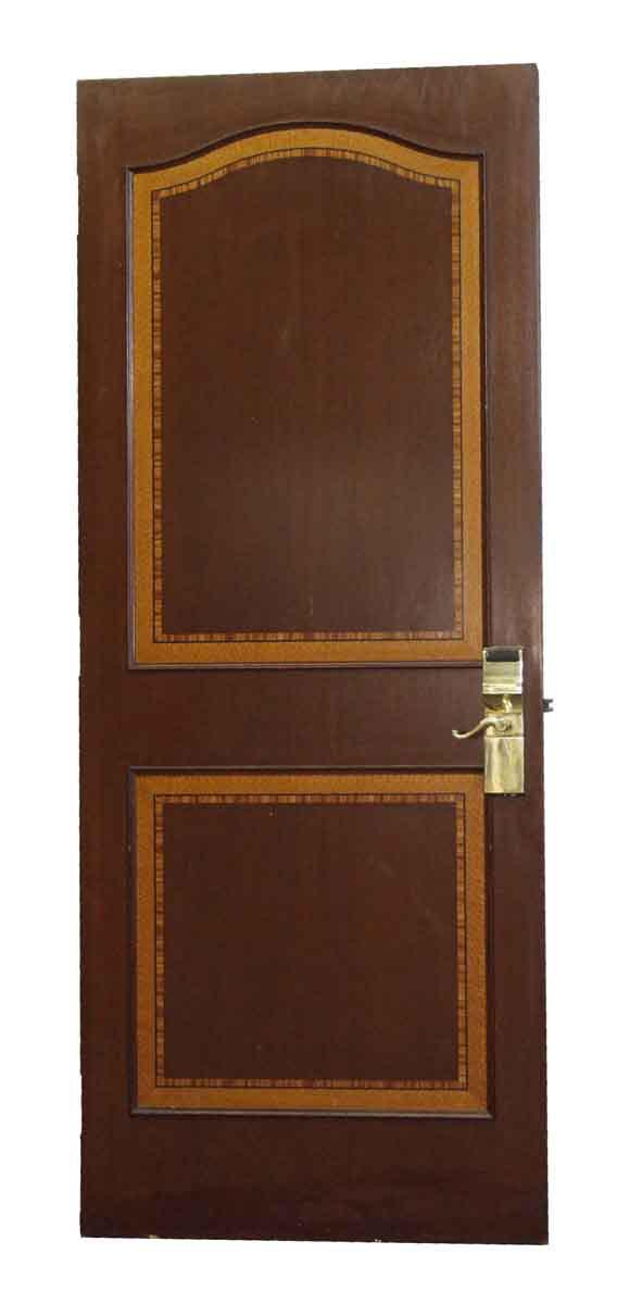 French-style wooden door with two outlined panels and a brass handle.