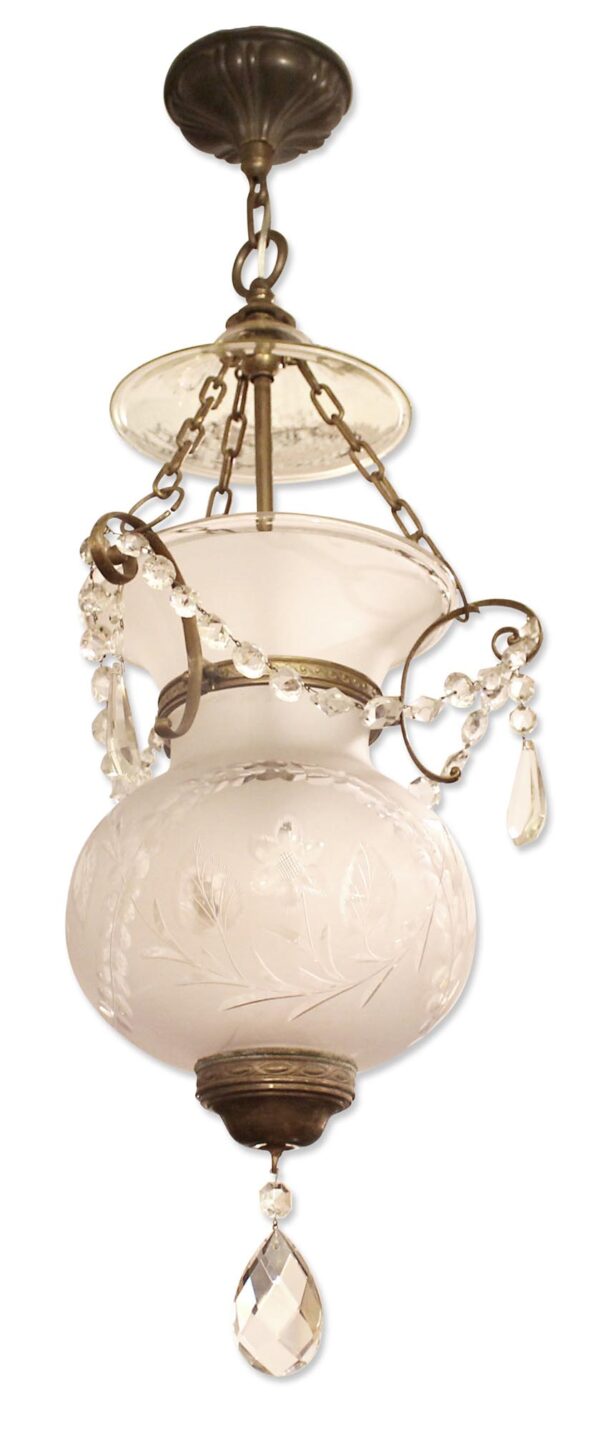 1930s traditional bell jar lantern with etched glass, crystal drops, and antique brass hardware, shown hanging in a close-up view.