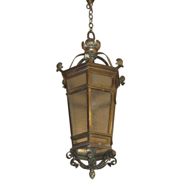 Antique traditional ceiling lantern with an antique bronze frame and enclosed pebble glass panels, shown hanging vertically with decorative cast details at the top and bottom.