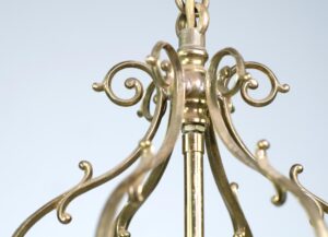Close-up of an antique brass pendant lantern with ornate scrollwork and a hanging chain connection.