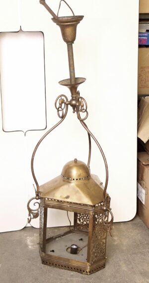 Handcrafted brass pendant ceiling lantern with ornate scrollwork and a domed top, shown without glass, hanging from a tall support and featuring a hexagonal lower section.