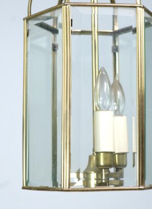 Traditional brass lantern light with hexagonal frame, clear beveled glass panes, and three candle-style bulbs.