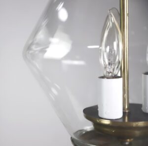 Close-up of a brass lantern light with a clear glass shade and one visible candle socket.